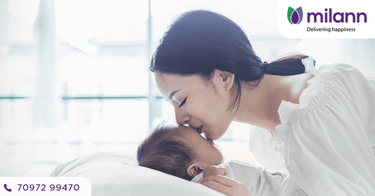 The mother embraces the infant with a kiss realizing how pregnancy loss can feel.